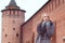 Beautiful blonde girl in a brown coat with fur looks into the distance against the background of the Marinkina tower in Kolomna