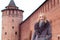 Beautiful blonde girl in a brown coat with fur posing on the background of the Marinkina tower in Kolomna