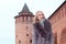 Beautiful blonde girl in a brown coat with fur posing on the background of the Marinkina tower in Kolomna