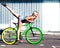 Beautiful blonde girl doing tricks and having fun on the steep green fixed bicycle in the city park of Europe