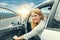Beautiful blonde girl driving a car on the highway. Invitation to travel. Car rental or vacation.