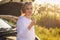 Beautiful blonde girl is engaged in repairing a car on a country road and holds a wrench and spark plugs in the rays