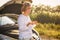 Beautiful blonde girl is engaged in repairing a car on a country road and holds a wrench and spark plugs in the rays