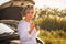 Beautiful blonde girl is engaged in repairing a car on a country road and holds a wrench and spark plugs in the rays of the sunset