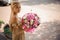 Beautiful blonde girl holds magnificent bouquet of flowers and looks at camera.