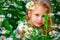 Beautiful blonde girl laughing in a field of daisies at sunset with a bouquet of camomiles