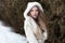 Beautiful blonde girl with long hair, full lips in a white coat walking in the winter woods
