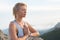 Beautiful blonde girl meditating on the top of the high rocky mountain in Malibu, USA