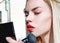 Beautiful blonde girl powdering her face with a brush, cosmetics and beauty concept