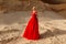 Beautiful blonde girl in a princess red dress posing in the desert. Fashionable model posing in red dress at the sunset.