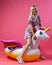 A beautiful blonde girl in a sexy sundress with slim legs in white sneakers stands on an inflatable multi-colored unicorn on a