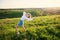 Beautiful blonde girl in straw hat standing in gymnastic pose on meadow at sunset