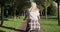 Beautiful blonde girl teenager rides bicycle in park, view from the back
