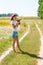 Beautiful blonde girl walking barefoot on summer field with a bouquet of wild flowers