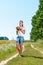 Beautiful blonde girl walking barefoot on summer field with a bouquet of wild flowers