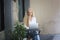 Beautiful blonde hair girl sitting with laptop in front of retails shop,Small business owner concept.