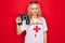 Beautiful blonde lifeguard woman wearing t-shirt with red cross and whistle using binoculars thinking attitude and sober