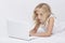 Beautiful blonde little girl with netbook, white background