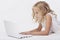 Beautiful blonde little girl with netbook, white background