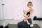 A beautiful blonde mother with a small child in her arms is sitting in the room on the floor after fitness. Doing sports