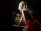 Beautiful blonde musician in red corset standing near the piano. Vintage style beautiful woman.