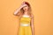 Beautiful blonde pin-up woman with blue eyes wearing diadem standing over yellow background making fun of people with fingers on
