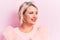 Beautiful blonde plus size woman wearing pincess tiara with diamonds over pink background looking to side, relax profile pose with