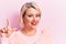 Beautiful blonde plus size woman wearing pincess tiara with diamonds over pink background smiling with an idea or question