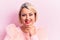 Beautiful blonde plus size woman wearing pincess tiara with diamonds over pink background smiling looking confident at the camera