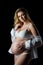 Beautiful blonde pregnant woman in white clothes on a black background. Women`s health and happy pregnancy