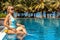 Beautiful blonde relaxes sunbathes near the pool on vacation