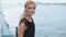 Beautiful blonde sitting on the outdoor deck of a ship in a black dress