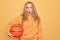 Beautiful blonde sportswoman doing sport holding basketball ball over yellow background scared and amazed with open mouth for