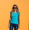 Beautiful blonde in sunglasses look at the camera. Portrait on the background of bright orange wall. Modern hipster girl