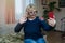 Beautiful blonde woman 50-60 years old waving hand greeting, looking into smartphone at home. Grandma is making a video