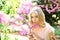 Beautiful blonde woman in blooming lilac garden, nature background. Young woman enjoy flowers in garden, defocused