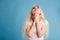 Beautiful blonde woman closes her eyes and pleading for the best on blue background
