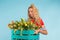 Beautiful blonde woman gardener holding box with tulips on blue background