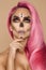 Beautiful blonde woman in Halloween makeup and in pink hair on a beige background in the studio. Makeup artist skeleton, monster,