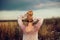 Beautiful blonde woman with long hair standing in a rural flower field outdoors, raising her hair