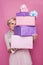 Beautiful blonde woman looking through colorful gift boxes. Soft colors. Christmas, birthday, Valentine day, present