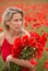 Beautiful blonde woman in poppy field with flowers