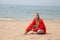 Beautiful blonde woman sits on an empty beach by the ocean