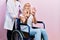Beautiful blonde woman sitting on wheelchair with collar neck afraid and terrified with fear expression stop gesture with hands,