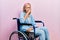 Beautiful blonde woman sitting on wheelchair feeling unwell and coughing as symptom for cold or bronchitis