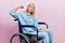 Beautiful blonde woman sitting on wheelchair strong person showing arm muscle, confident and proud of power