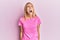 Beautiful blonde woman wearing casual pink tshirt angry and mad screaming frustrated and furious, shouting with anger