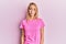 Beautiful blonde woman wearing casual pink tshirt looking sleepy and tired, exhausted for fatigue and hangover, lazy eyes in the