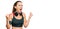 Beautiful blonde woman wearing gym clothes and using headphones crazy and mad shouting and yelling with aggressive expression and