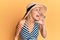 Beautiful blonde woman wearing summer hat shouting and screaming loud to side with hand on mouth